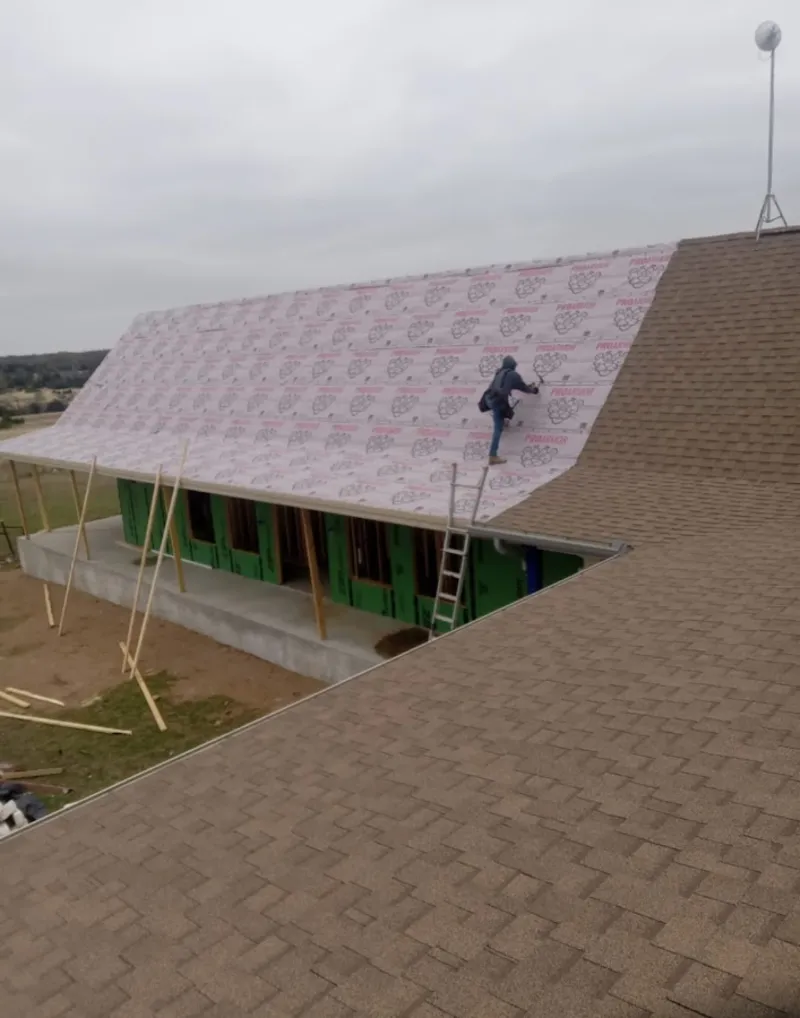 Worker preparing underlayment for a metal roof installation in The Village